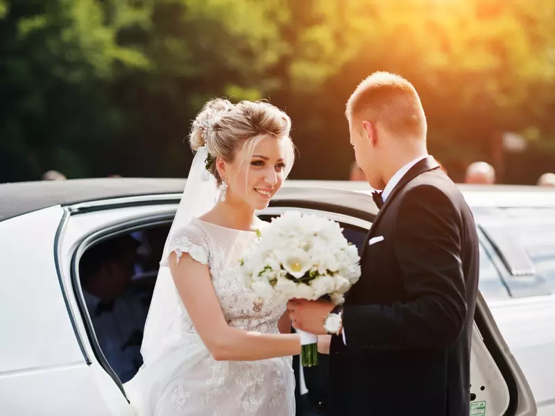 Młoda para wsiadająca do białej długiej limuzyny
